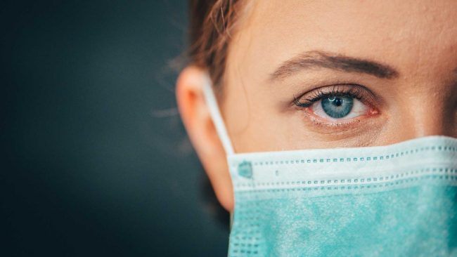 Close-up of woman wearing a disposable mask over her nose and mouth.